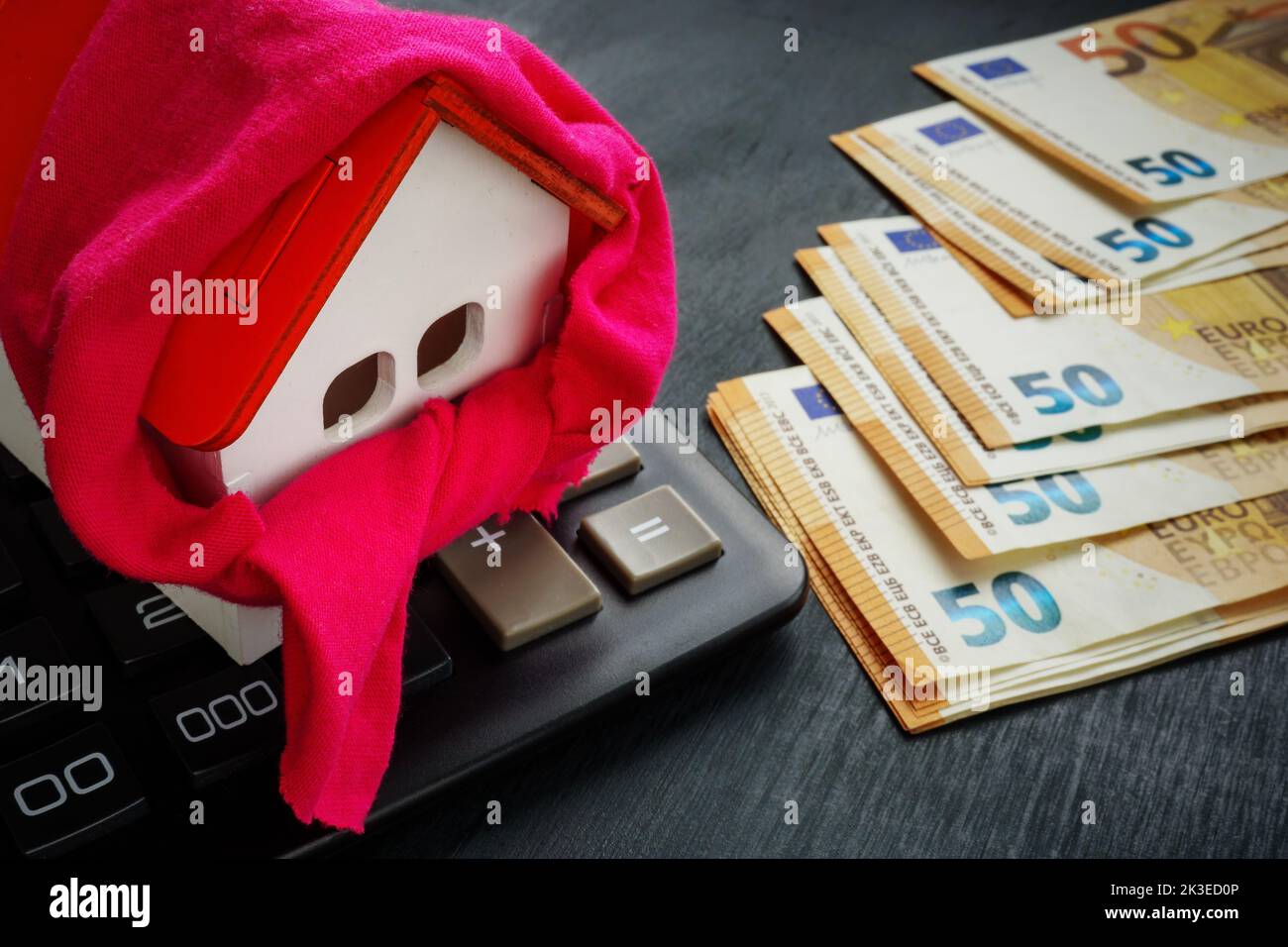 Modelo de casa con bufanda, euro y calculadora. Concepto de calefacción y aislamiento. Foto de stock