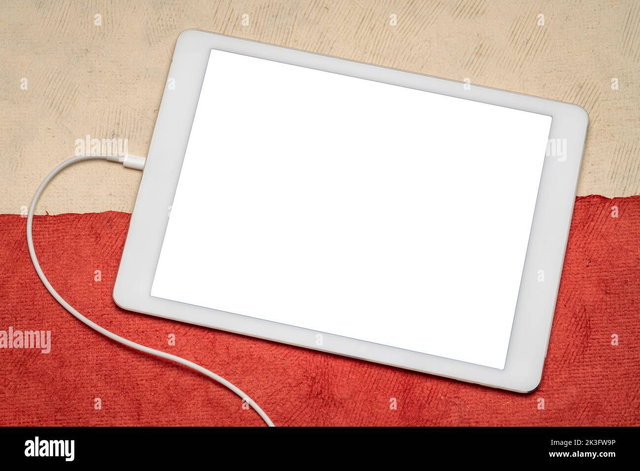 Maqueta de tableta digital con una pantalla aislada en blanco (ruta de recorte incluida) sobre papel abstracto en colores de bandera nacional polaca, blanco y rojo Foto de stock