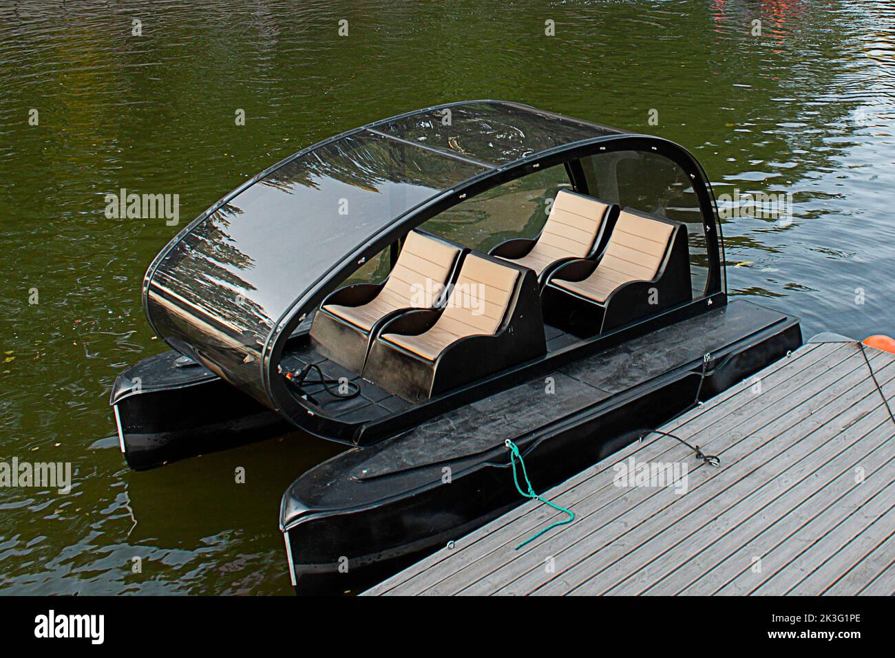 Catamarán eléctrico de cuatro plazas en el muelle de madera, enfoque selectivo. Alquiler de barcos pontón compacto Foto de stock