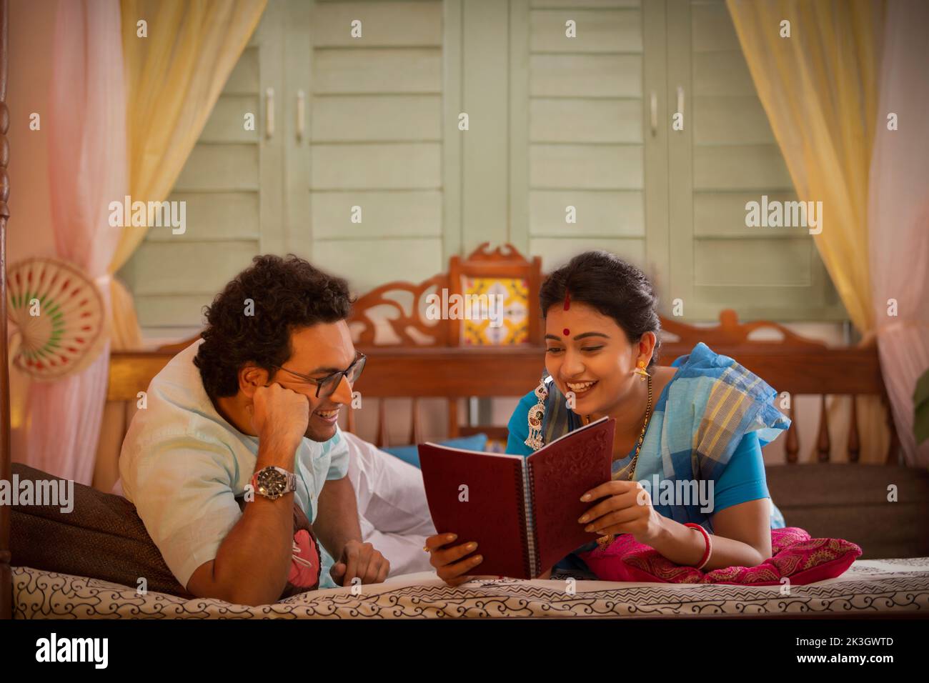 Retrato de una pareja bengalí leyendo un libro en la cama Foto de stock