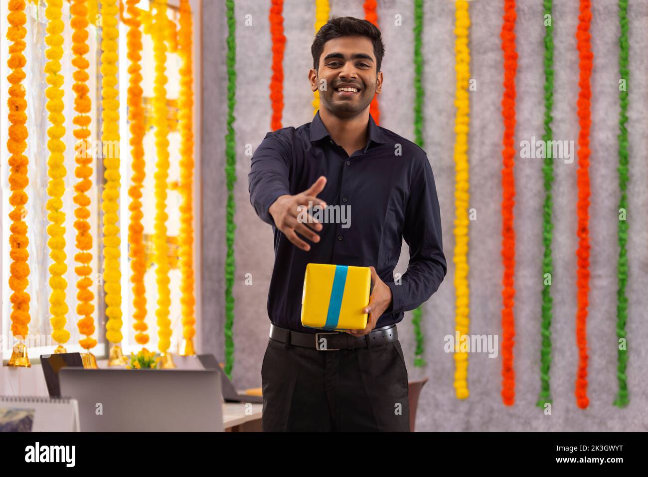 Retrato de un joven sonriente a punto de estrechar la mano en el cargo durante la celebración de Diwali Foto de stock