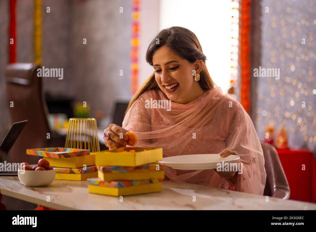 Mujer joven arreglando ladoos en caja dulce en el cargo con ocasión de Diwali Foto de stock