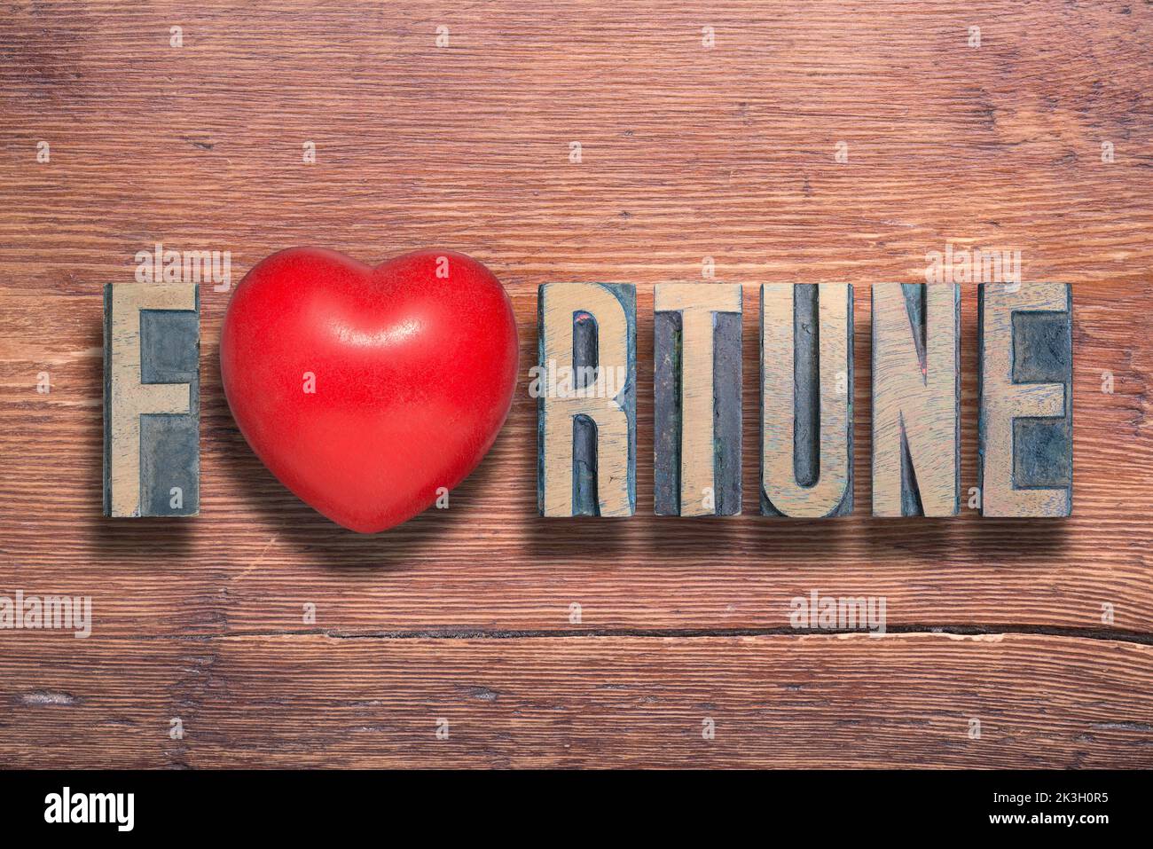 palabra de fortuna combinada en una superficie de madera barnizada vintage con un símbolo de corazón en su interior Foto de stock
