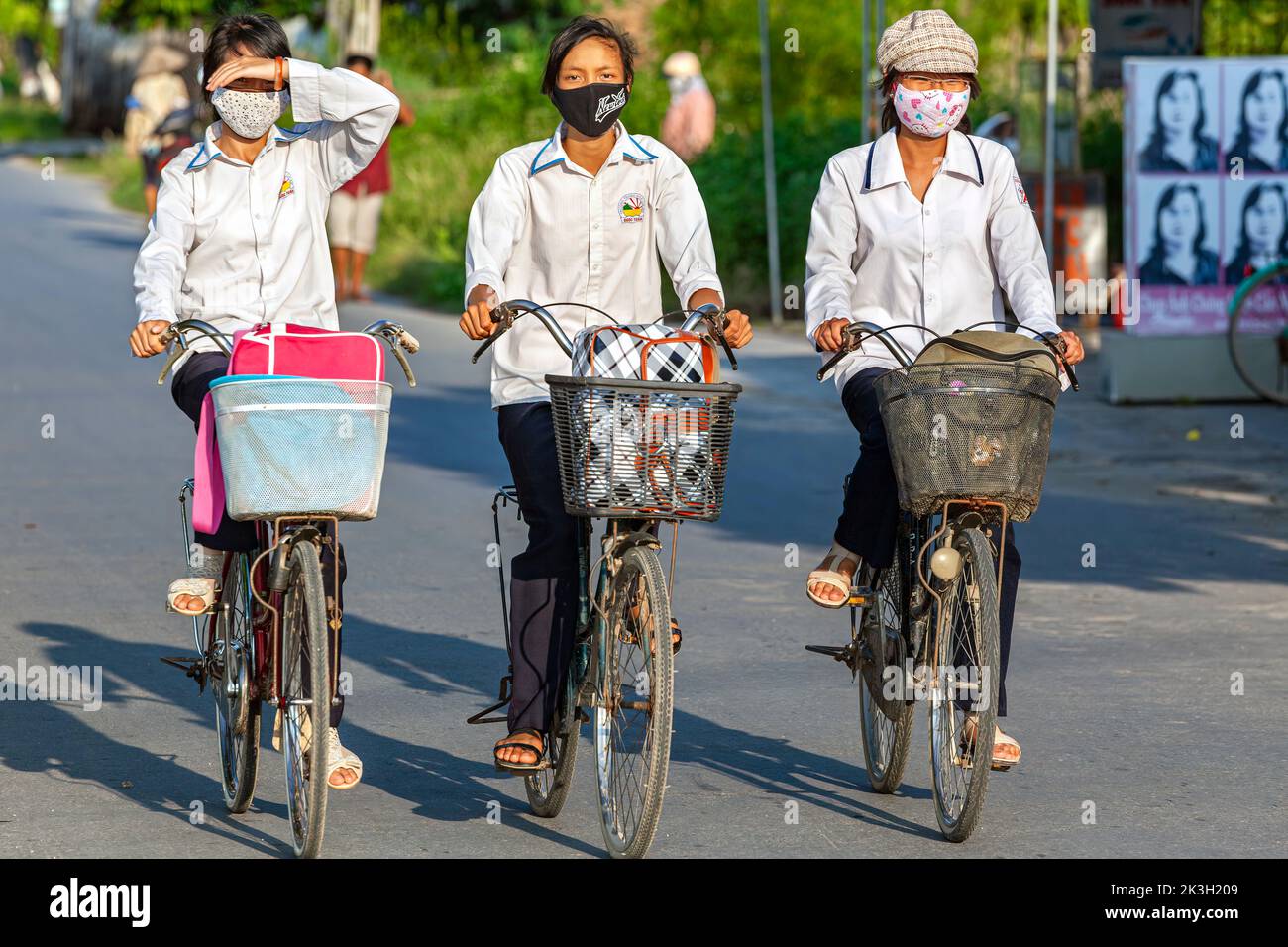 Estudiantes vietnamitas en bicicleta por carretera rural, Hai Phong, Vietnam Foto de stock