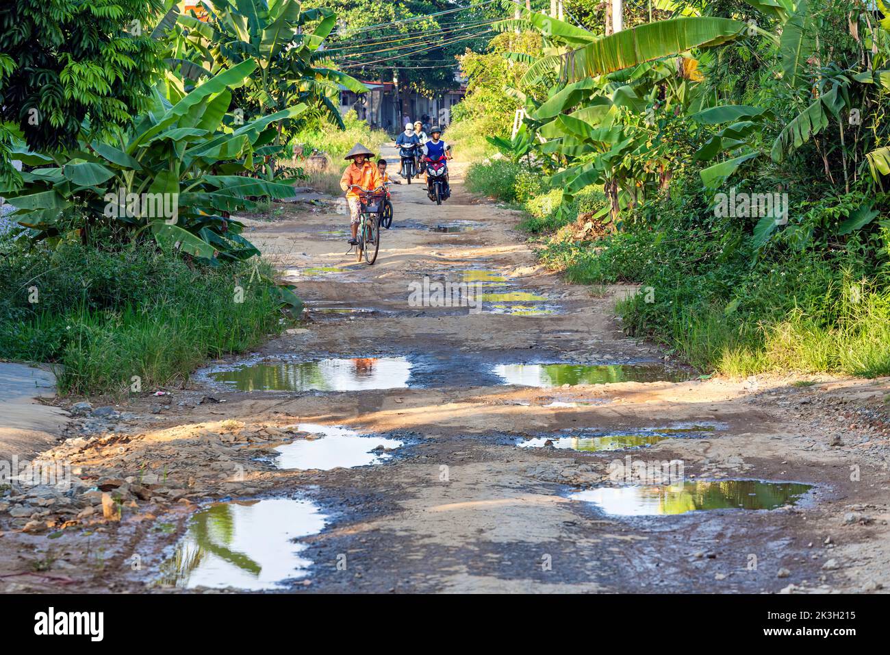 Baches y tráfico en carretera rural no pavimentada, Hai Phong, Vietnam Foto de stock