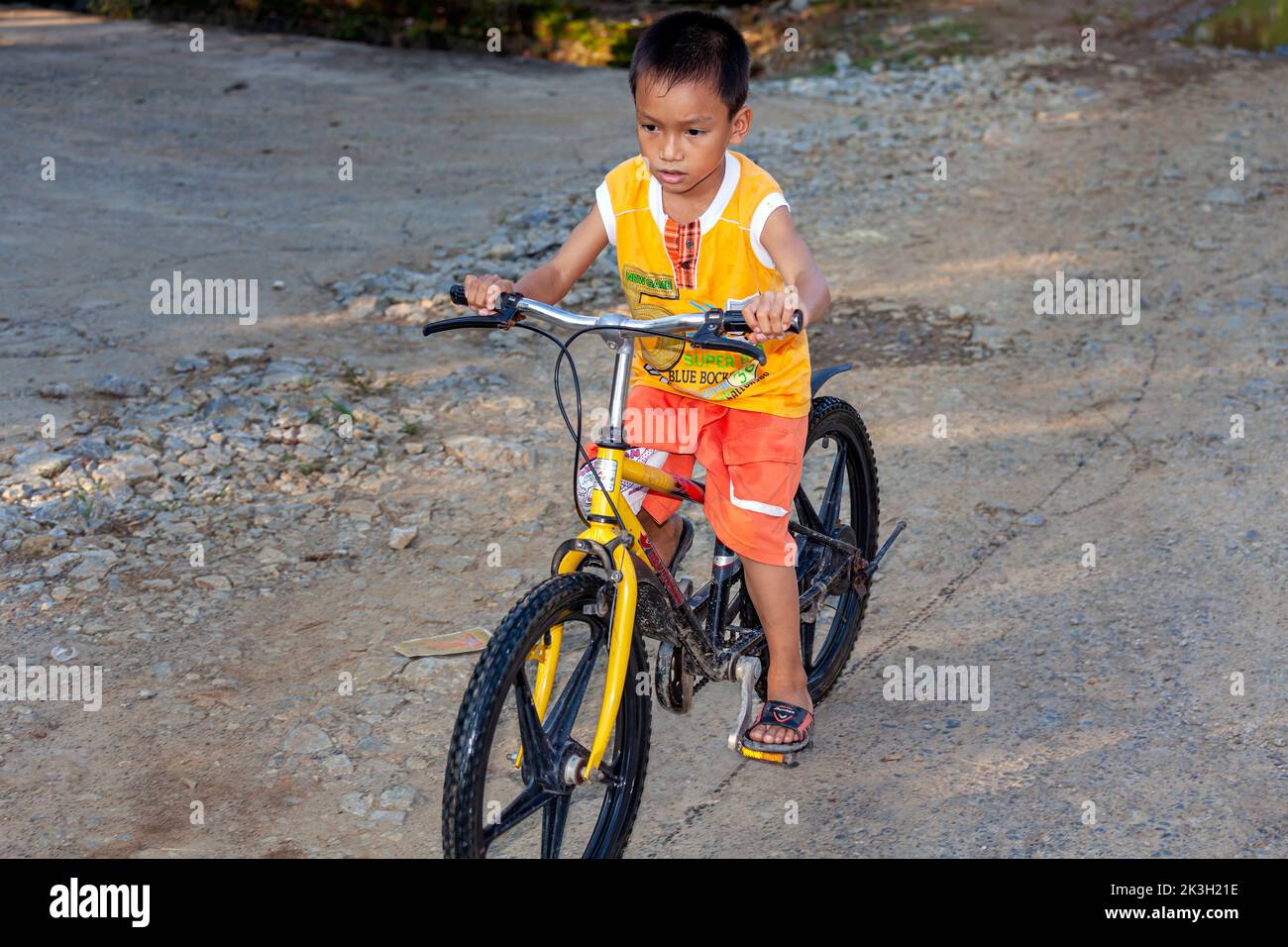 Niño pequeño en bicicleta pequeña en un camino sin pavimentar en la zona rural de Hai Phong, Vietnam Foto de stock