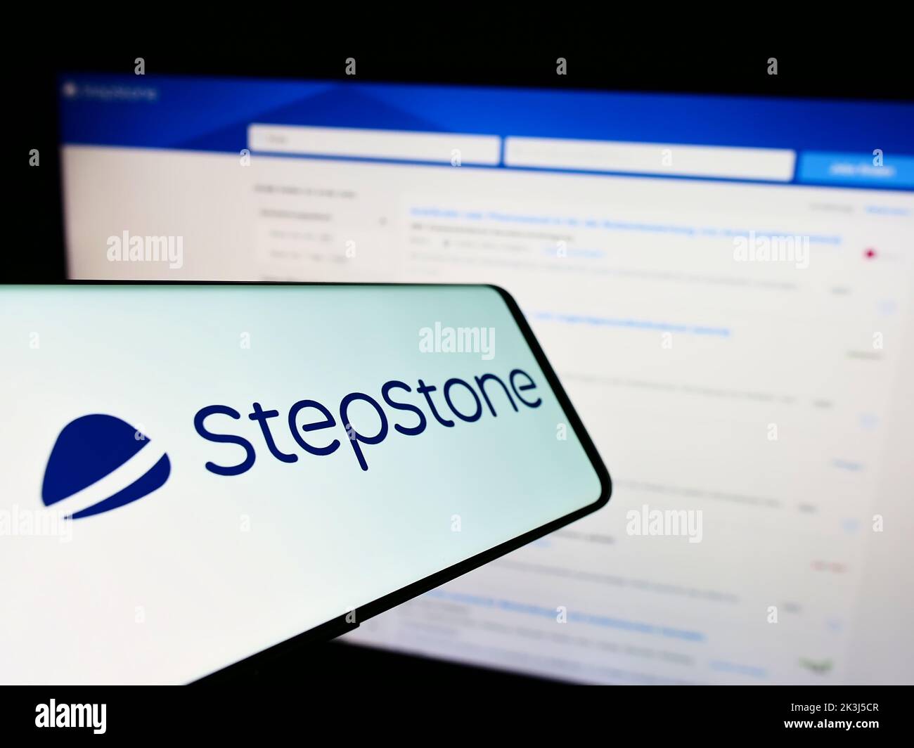 Smartphone con el logotipo de la empresa alemana StepStone GmbH en la pantalla delante del sitio web del negocio. Enfoque en el centro de la pantalla del teléfono. Foto de stock