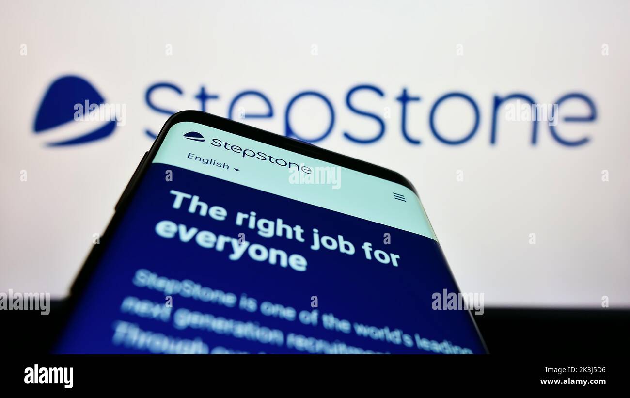 Teléfono móvil con sitio web de la empresa alemana StepStone GmbH en la pantalla delante del logotipo de la empresa. Enfoque en la parte superior izquierda de la pantalla del teléfono. Foto de stock