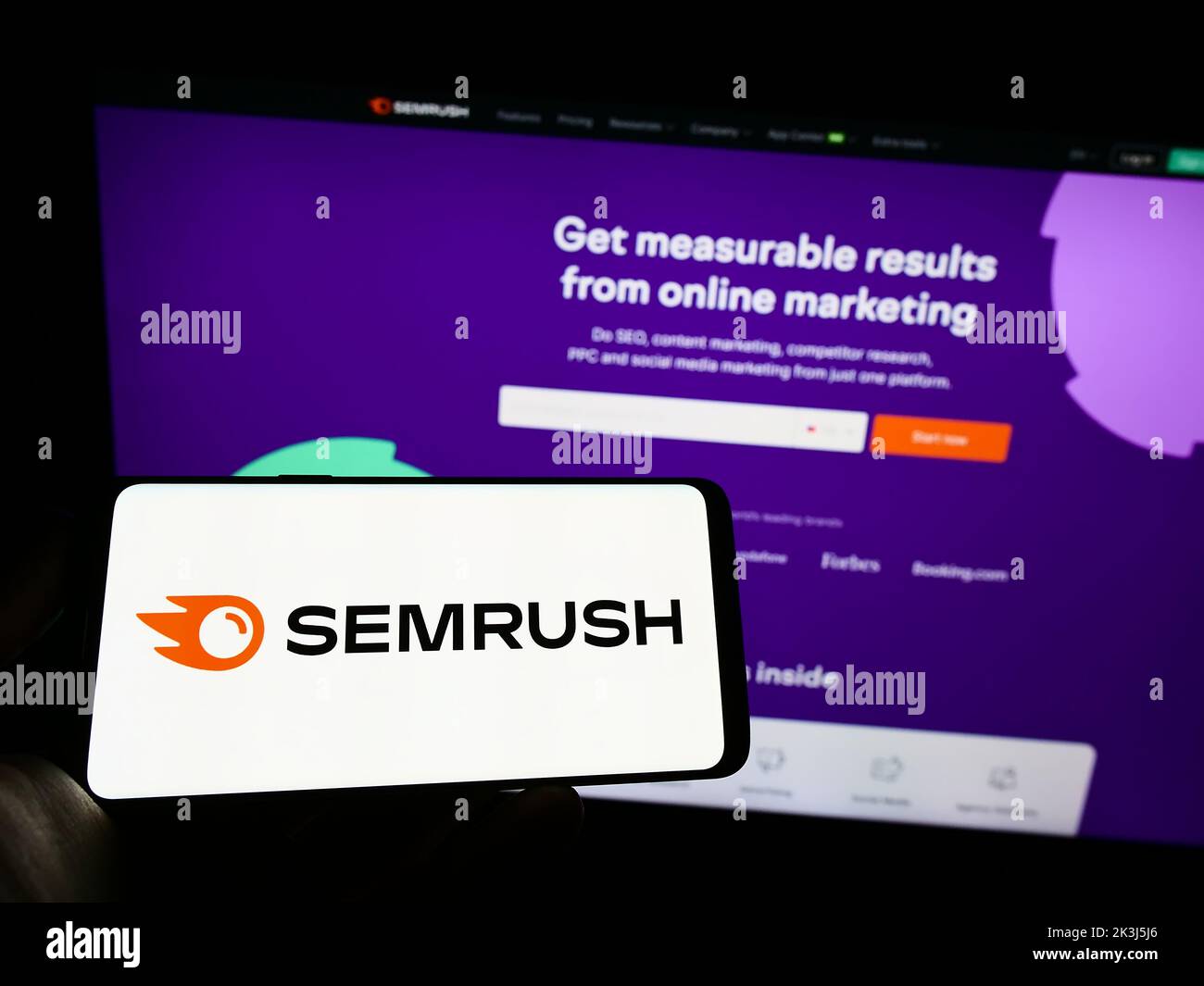 Persona que sostiene el teléfono móvil con el logotipo de la empresa de marketing de motores de búsqueda de EE.UU., SOMrush Inc. En la pantalla delante de la página web. Enfoque la pantalla del teléfono. Foto de stock