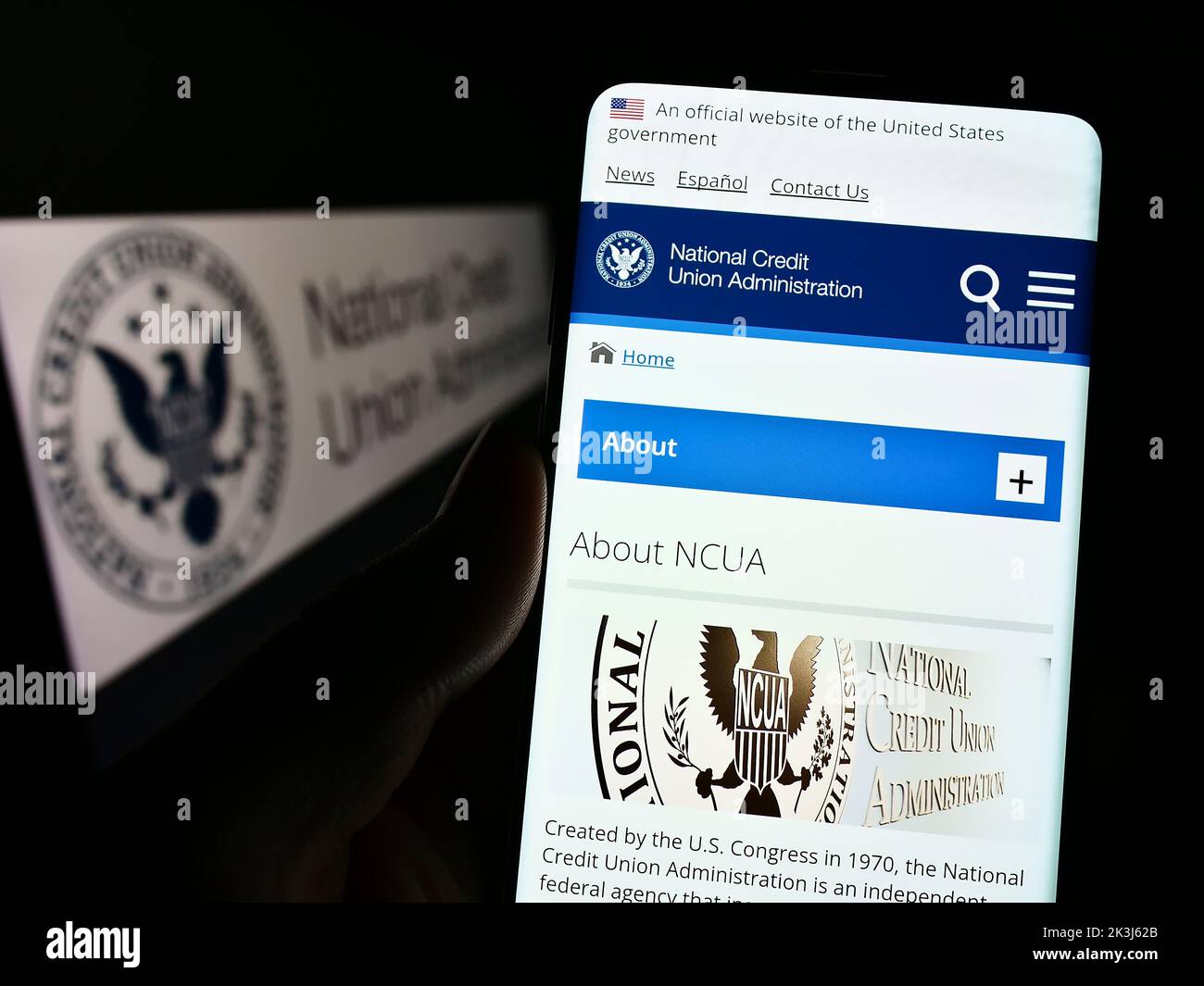 Persona con smartphone con sitio web de la Administración Nacional de Cooperativas de Ahorro y Crédito de EE.UU. (NCUA) en pantalla con logotipo. Enfoque en el centro de la pantalla del teléfono. Foto de stock