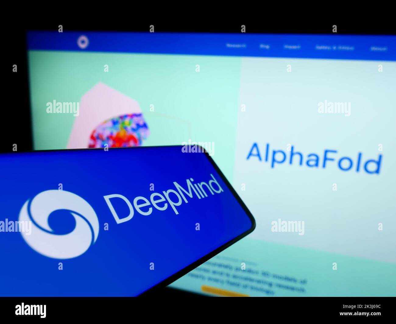 Teléfono móvil con el logotipo de la empresa de AI DeepMind Technologies Limited en la pantalla frente al sitio web del negocio. Enfoque en la parte derecha de la pantalla del teléfono. Foto de stock