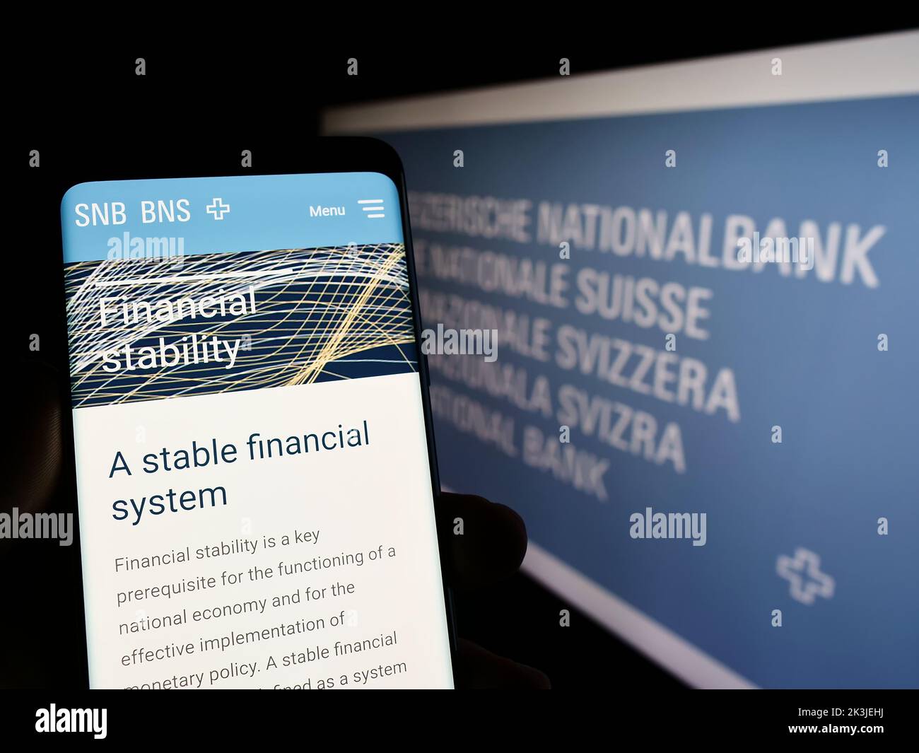Persona que sostiene el celular con la página web de la institución financiera Swiss National Bank (SNB) en pantalla con el logo. Enfoque en el centro de la pantalla del teléfono. Foto de stock