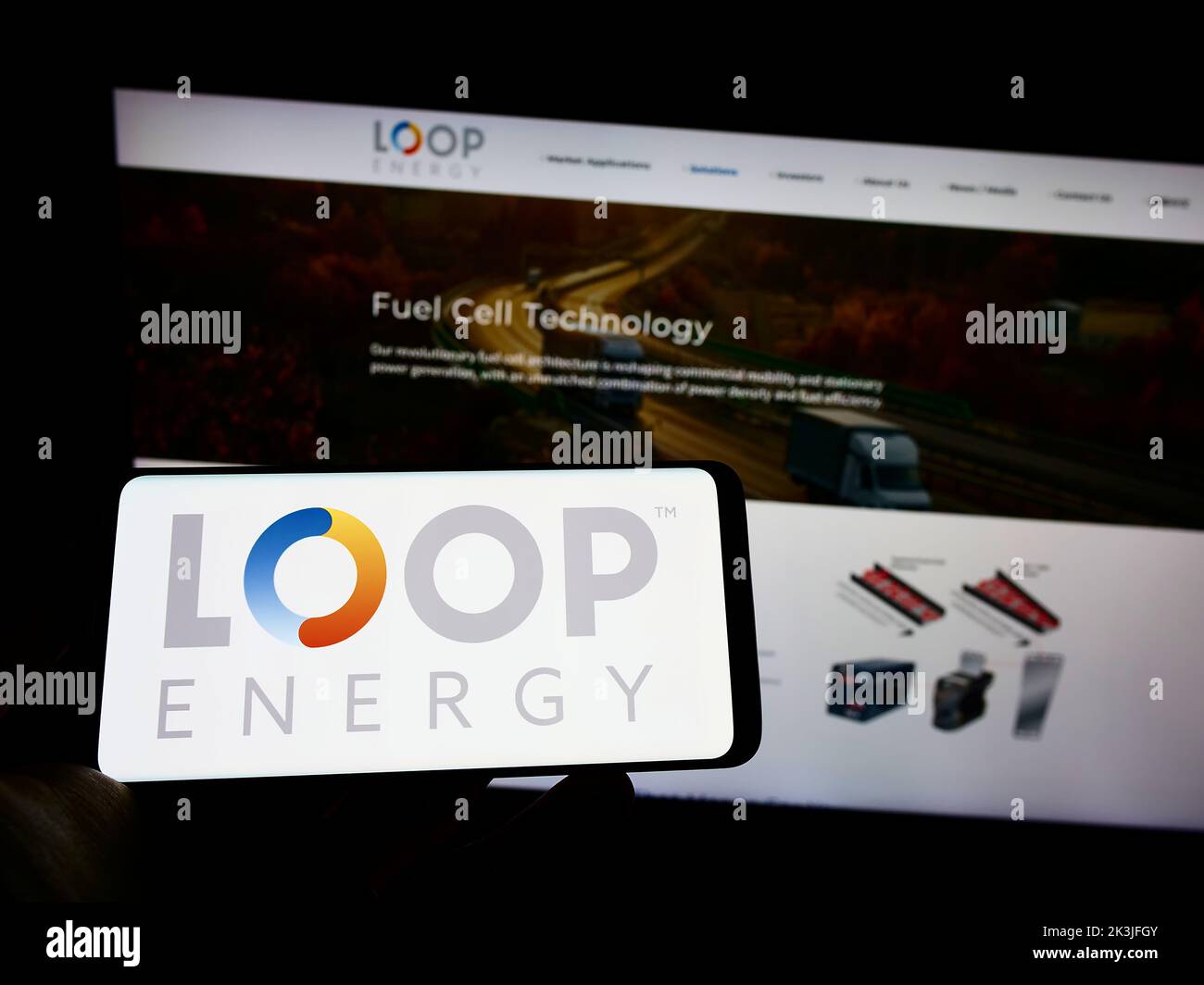 Persona que sostiene un smartphone con el logotipo de la compañía canadiense de hidrógeno Loop Energy Inc. En la pantalla delante del sitio web. Enfoque la pantalla del teléfono. Foto de stock