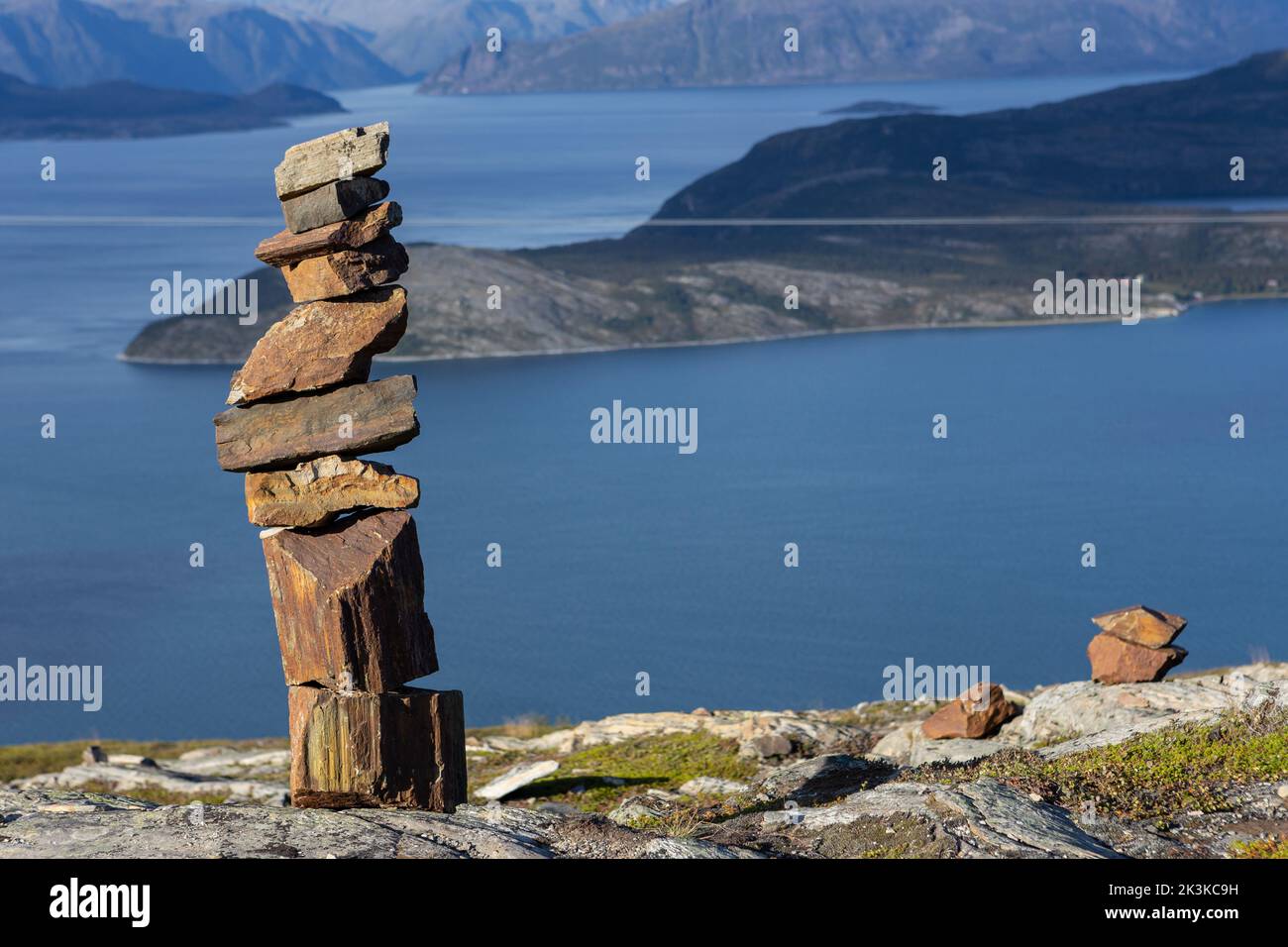 Montón de rocas en la cima de una montaña en Noruega, una roca en otra roca. El mar de Noruega y las islas en el fondo. Vista de arriba abajo. Foto de stock