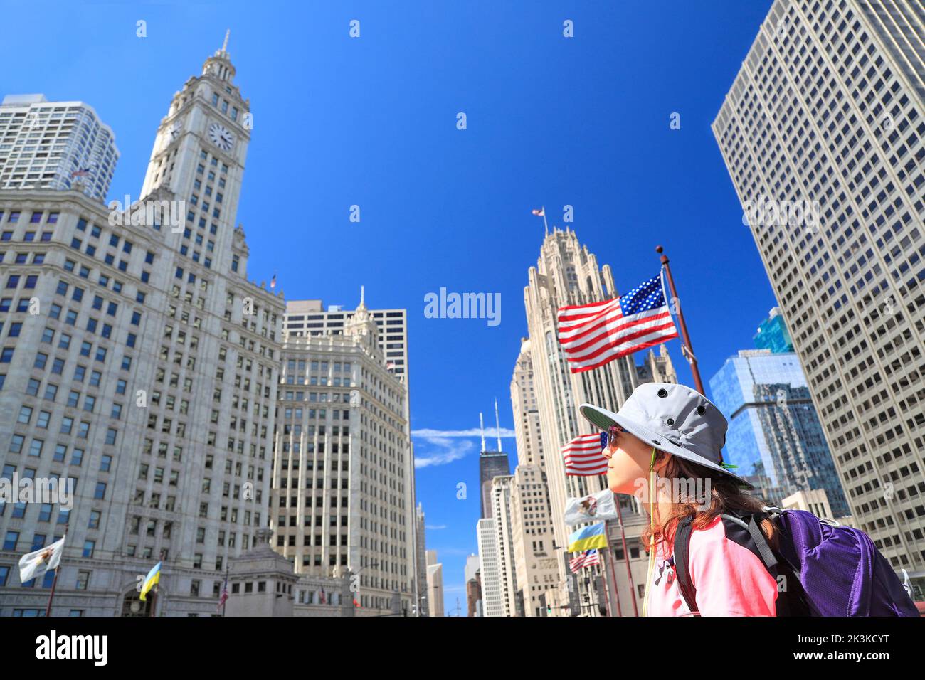 Adolescente turístico mientras admira el horizonte de Chicago en Michigan Avenue con la bandera americana en primer plano en Chicago, EE.UU Foto de stock