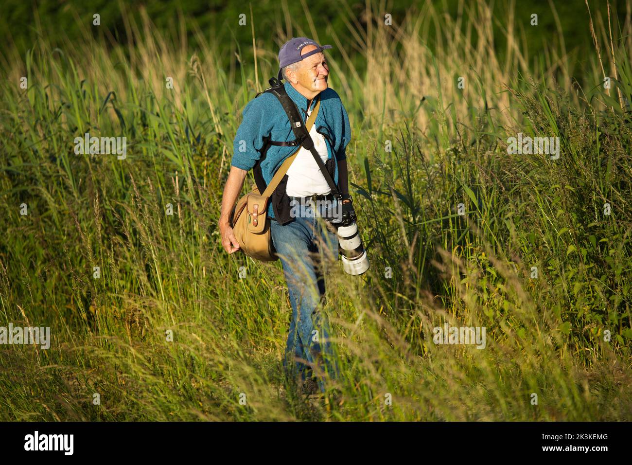 Un fotógrafo caminando al aire libre con su equipo de cámara Foto de stock