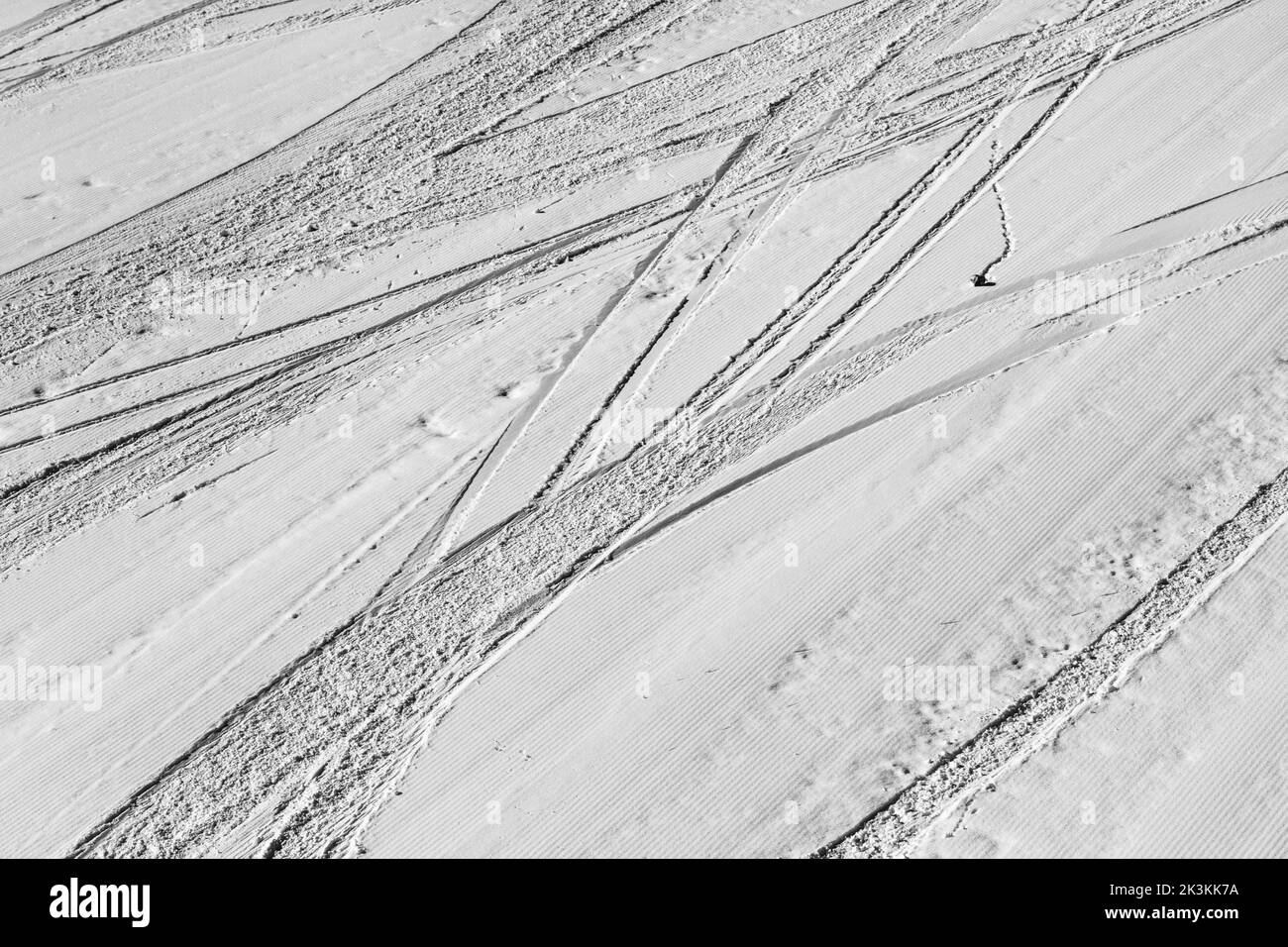 Pista de esquí cubierta de nieve acondicionada con rastro de esquís y snowboards en el soleado día de invierno. Blanco y negro. Alto contraste. Foto de stock