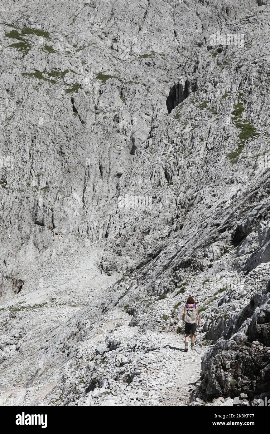 Mujer joven camina por el sendero de las Dolomitas en los Alpes europeos de la cadena montañosa llamada Grupo Pale en Italia Foto de stock