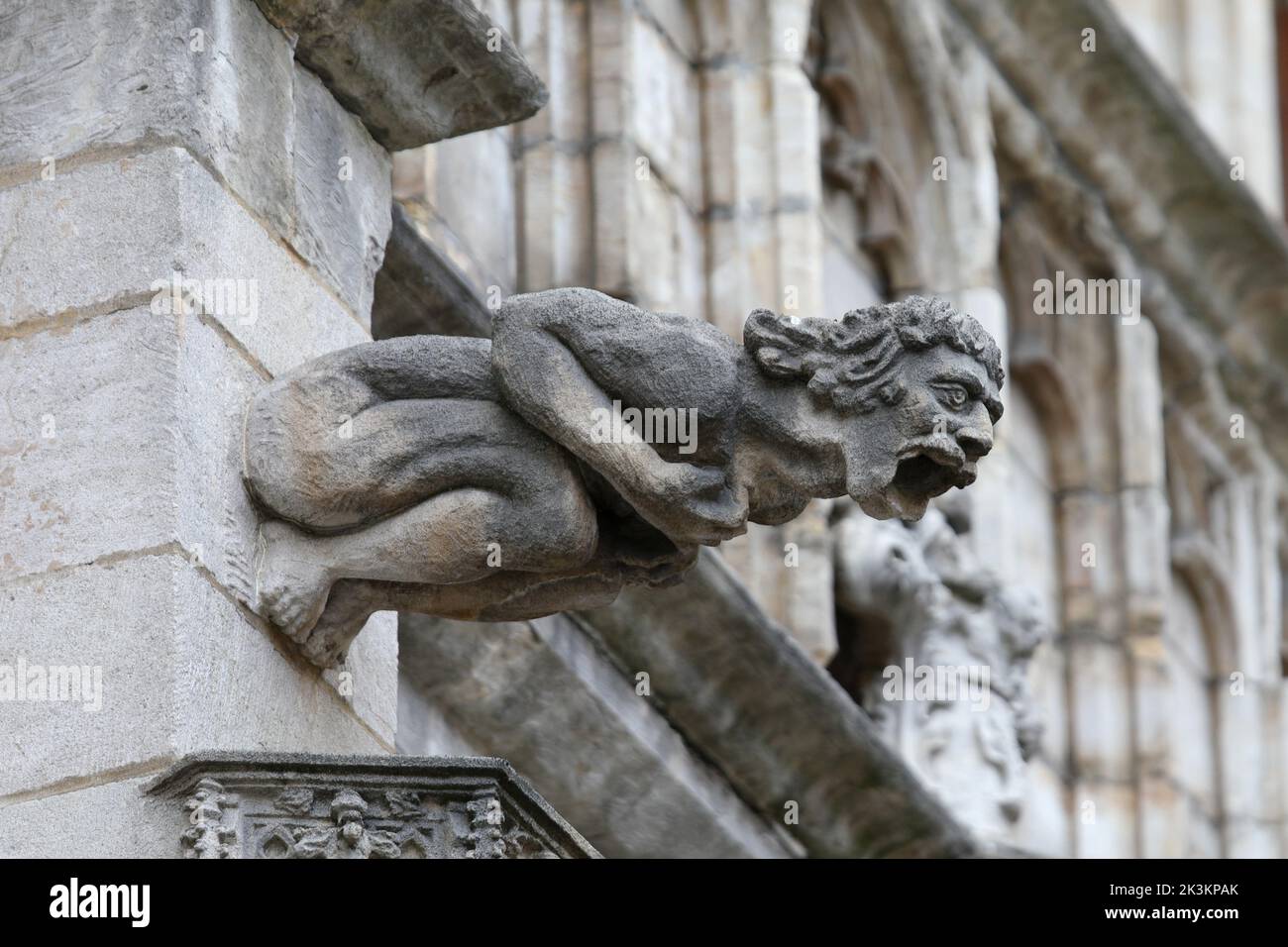 Estatua monstruosa con características casi humanas llamada gárgola en la fachada del edificio histórico Foto de stock
