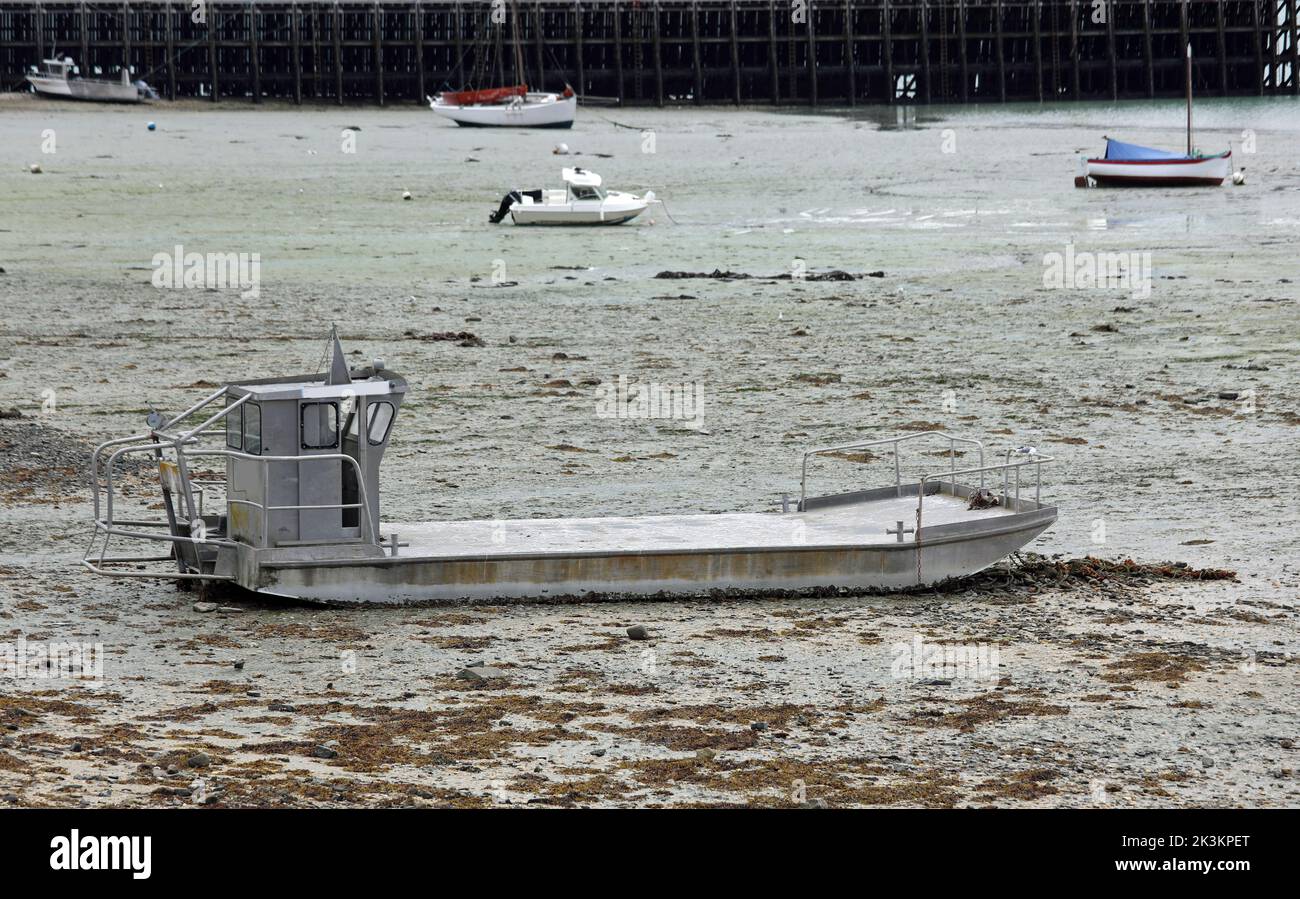 barcos varados y una gran barcaza en la arena fangosa durante la marea baja Foto de stock