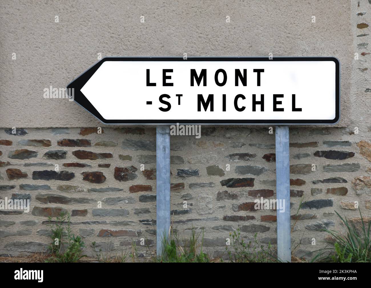 Señal de carretera con el texto Le Mont ST MICHEL y la flecha para llegar a la abadía normadiana en Francia Foto de stock