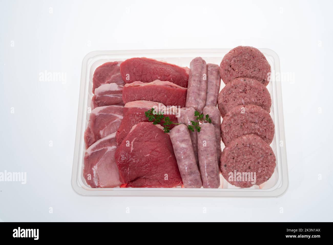 Una bandeja que contiene una selección de carnes frescas crudas con fondo blanco Foto de stock