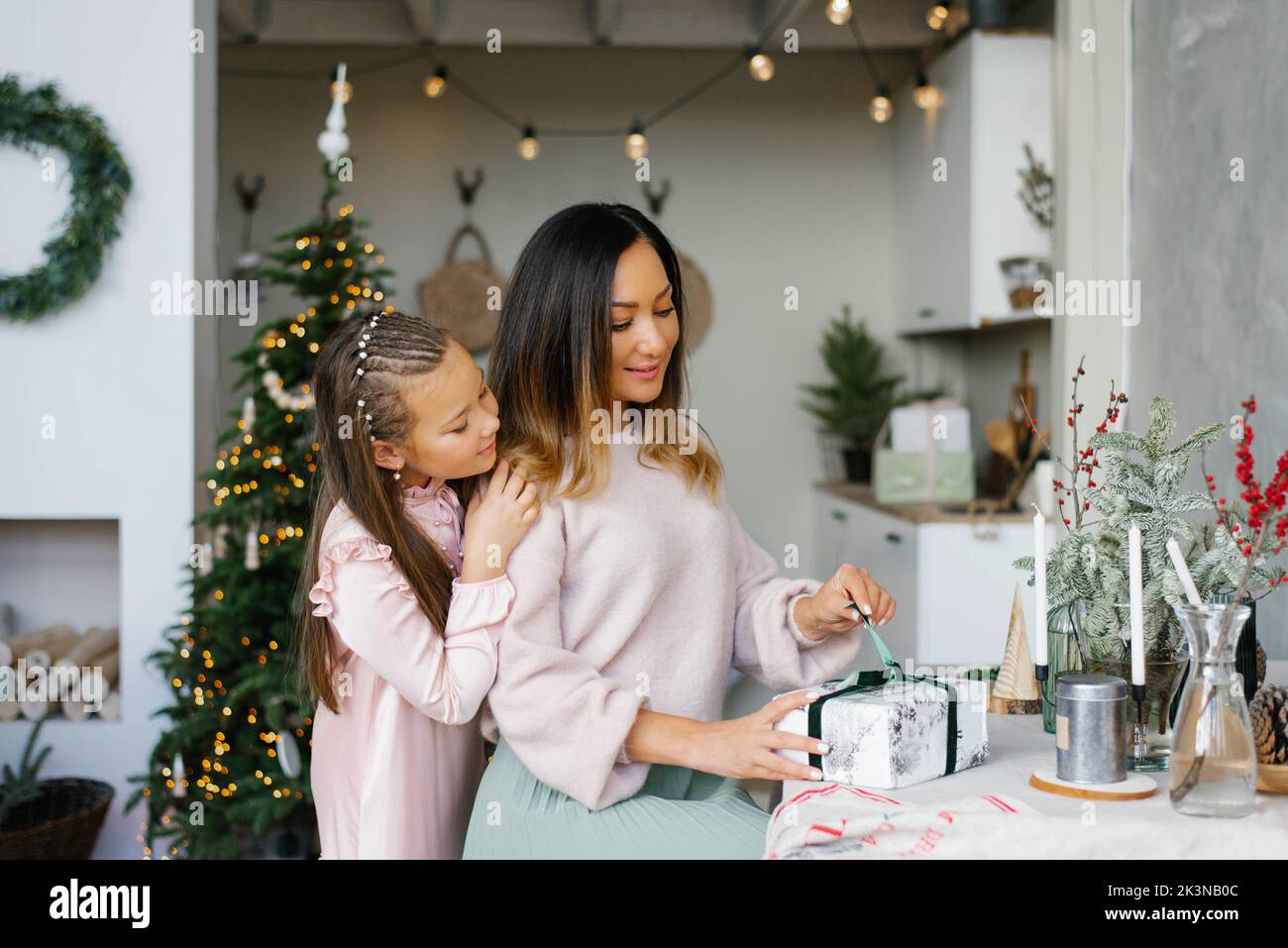 Madre abre un regalo de Navidad con su hija Foto de stock