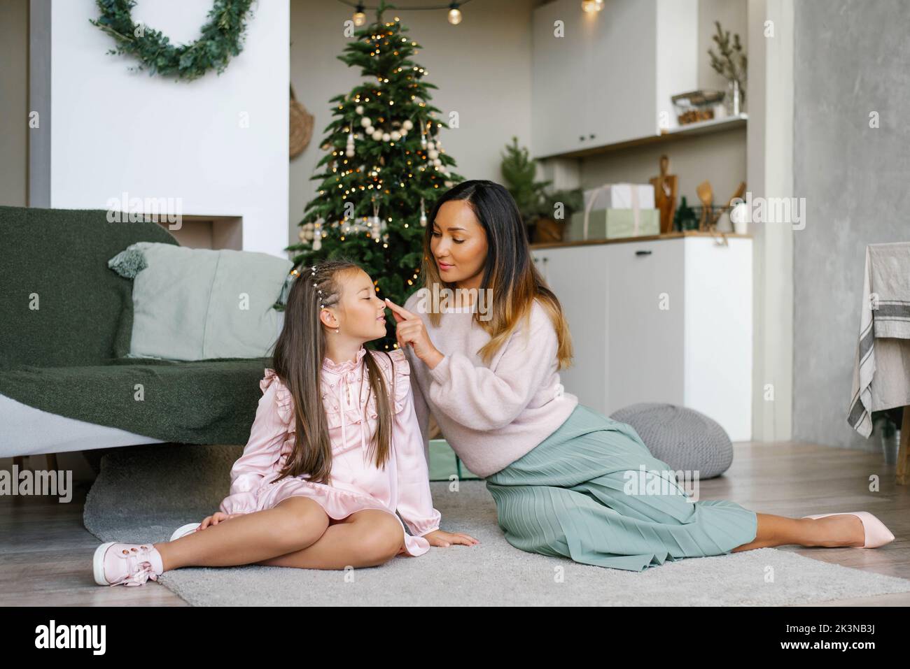 La madre toca la nariz de su hija con su dedo en la víspera de Navidad Foto de stock