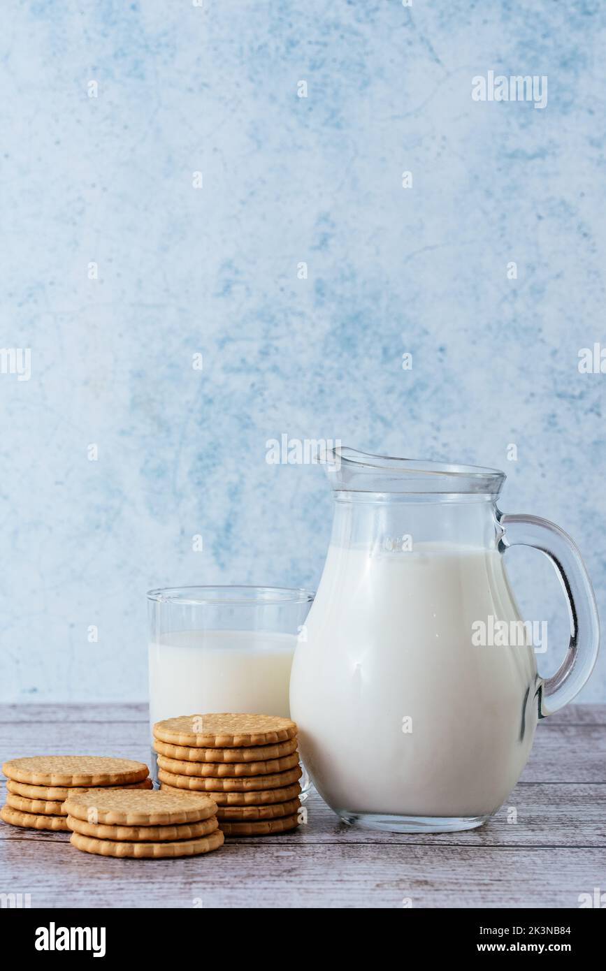 leche en una jarra y un vaso con galletas Foto de stock