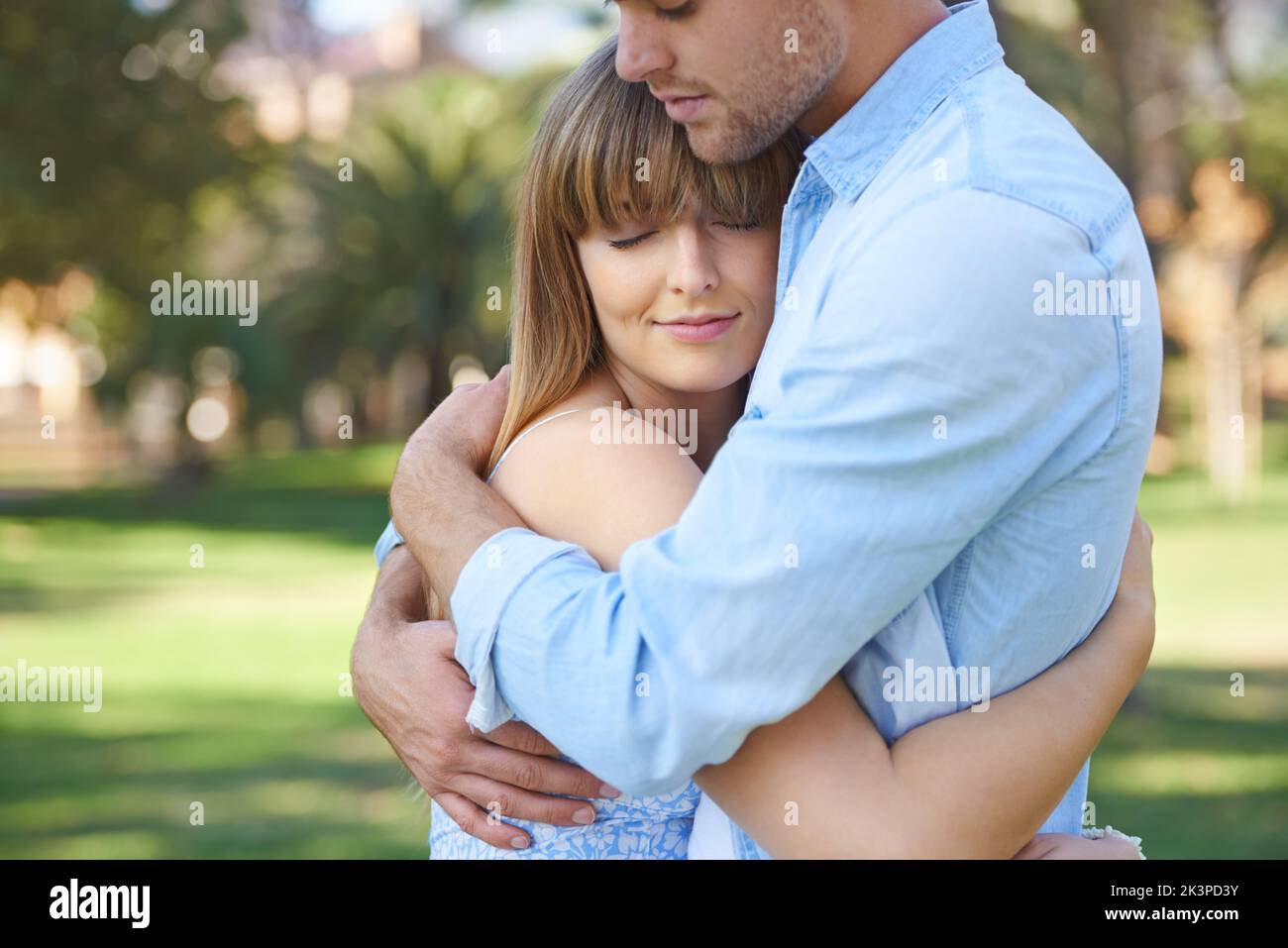 Cada día es soleado cuando estás enamorado... una joven pareja de brazos en brazos disfrutando de un día en el parque. Foto de stock