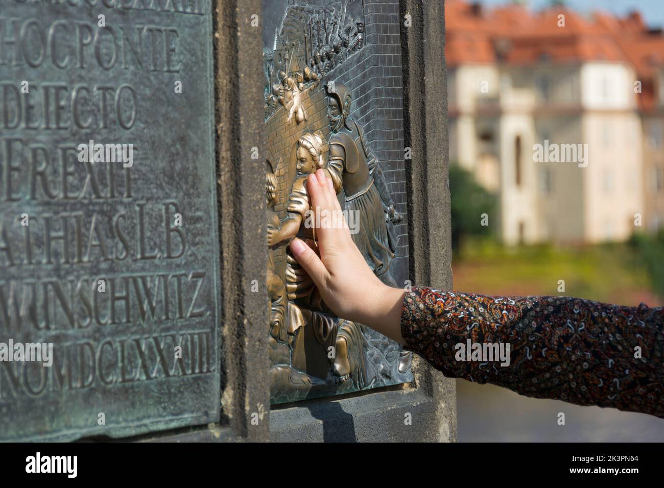Serie de fotos de Praga: La mano toca la placa de bronce de la estatua de Nepomuk en el Puente de Carlos en Praga Foto de stock