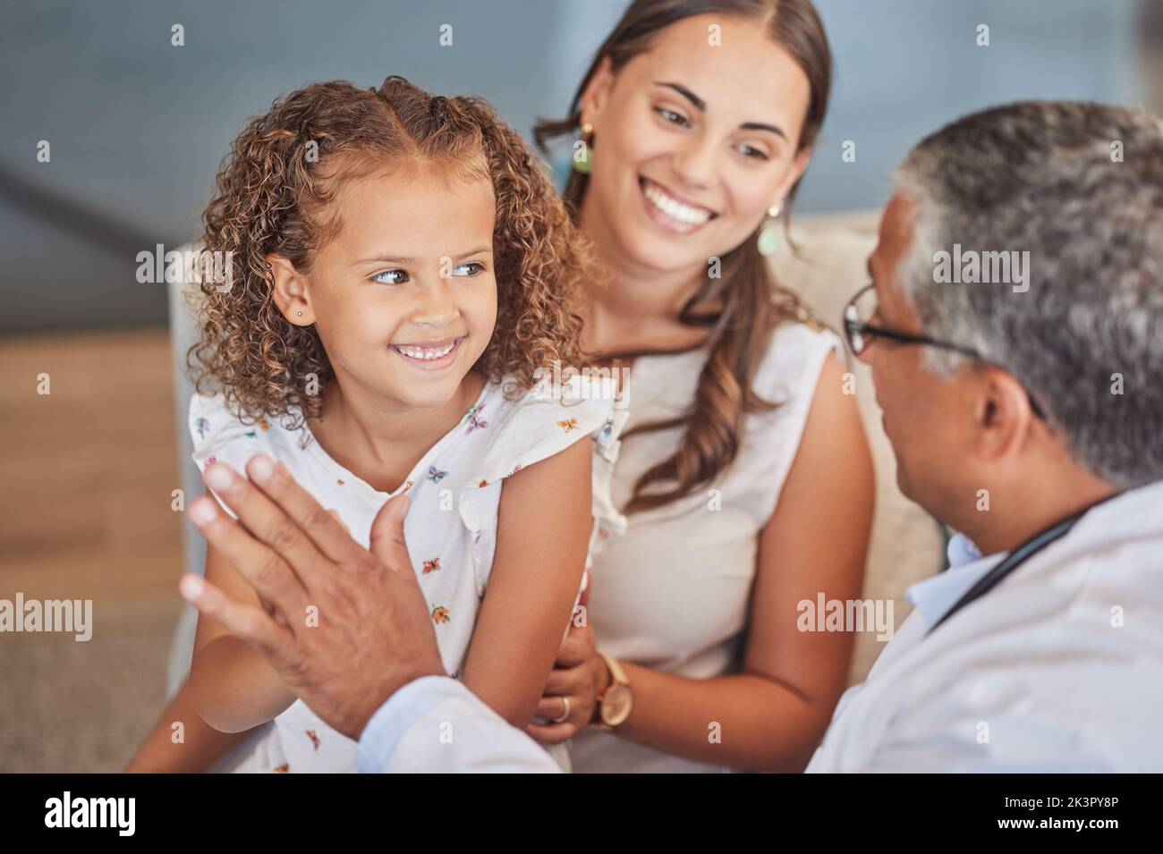 Niño médico, pediatra y alto cinco con paciente feliz de la muchacha con padre de la madre durante chequeo médico con seguro médico. Niño y mujer latina Foto de stock