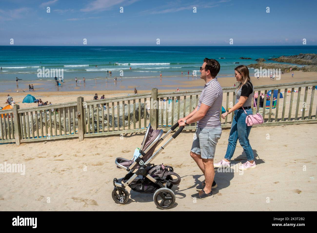 Una joven familia de vacaciones caminando a una concurrida playa de Fistral en Newquay en Cornwall en el Reino Unido. Foto de stock