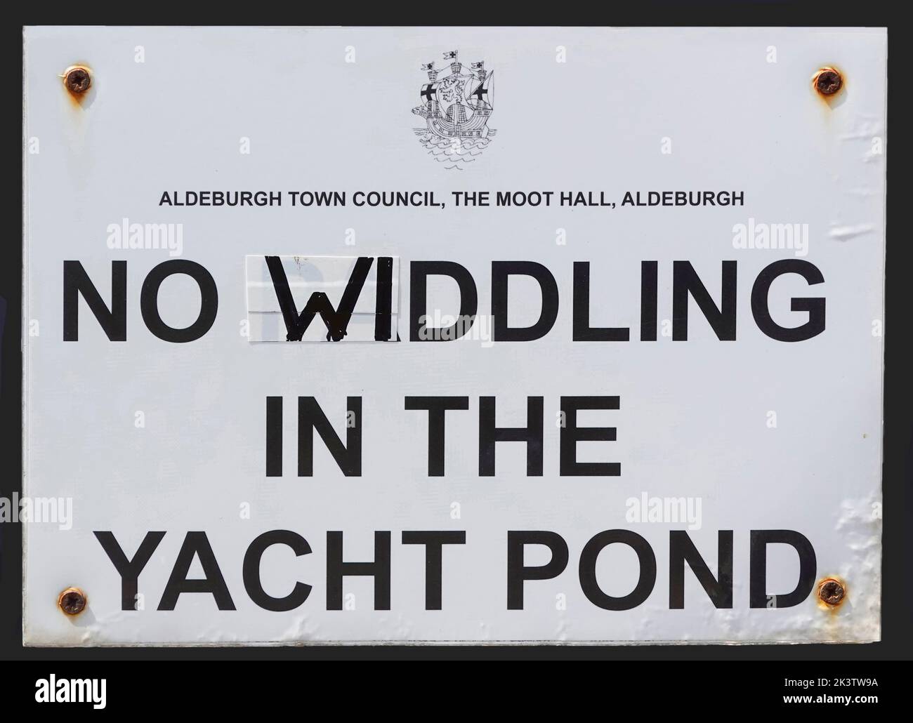 Aviso del Ayuntamiento de Aldeburgh en el pequeño estanque de yates poco profundo también utilizado por los niños remando originalmente requiriendo No Piddling modificado a Widdling, Suffolk Reino Unido Foto de stock