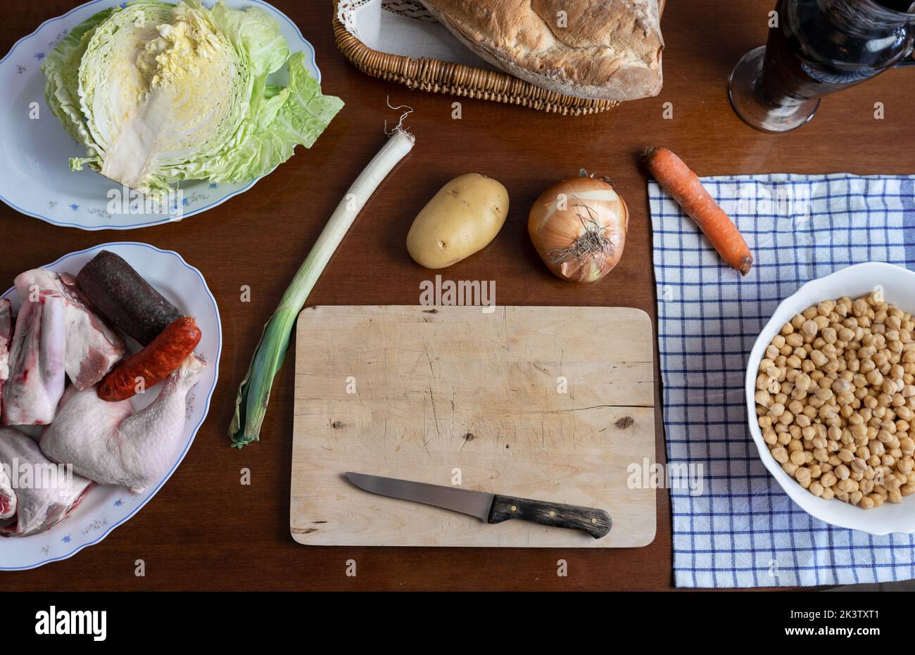 Desde arriba de zanahoria fresca cruda y cebolla colocada cerca de tabla de cortar de madera con cuchillo en la mesa cerca de luz del día Foto de stock