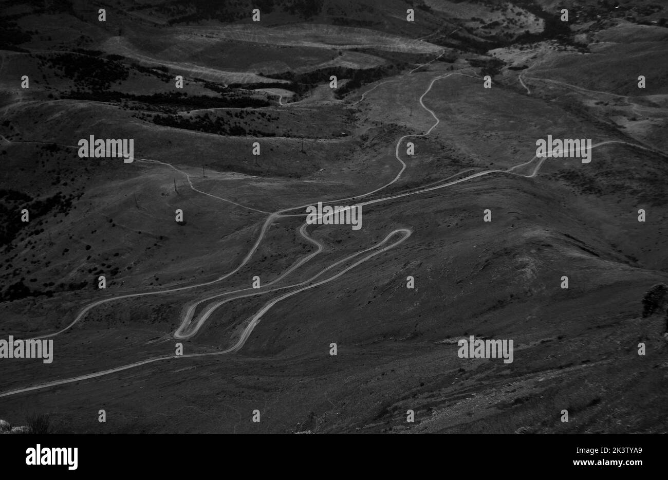 Una fotografía aérea en escala de grises de calles curvas en el paisaje montañoso Foto de stock