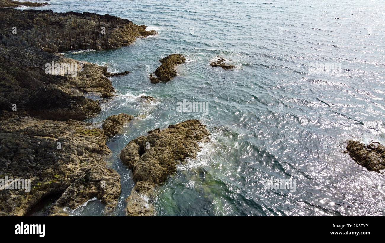 Salvaje costa rocosa del Océano Atlántico. Pequeñas ondas y el sol resplandece en la superficie del agua. Paisaje costero en un día soleado. Foto de stock