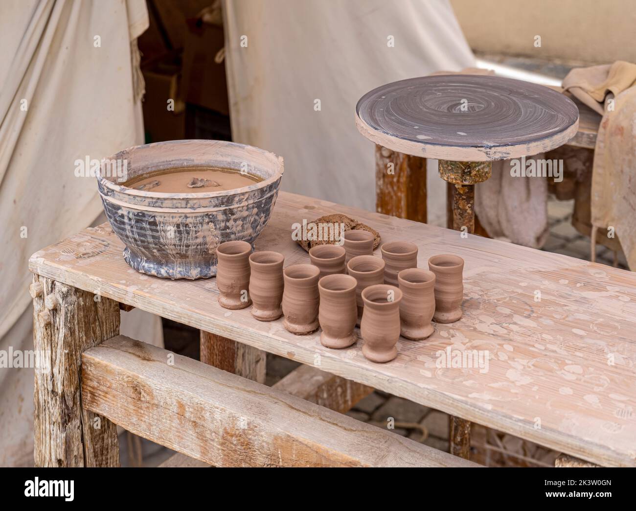 Fabricación tradicional de cerámica con mesa de lanzamiento, vasos de precipitado y cuenco sobre mesa de madera Foto de stock