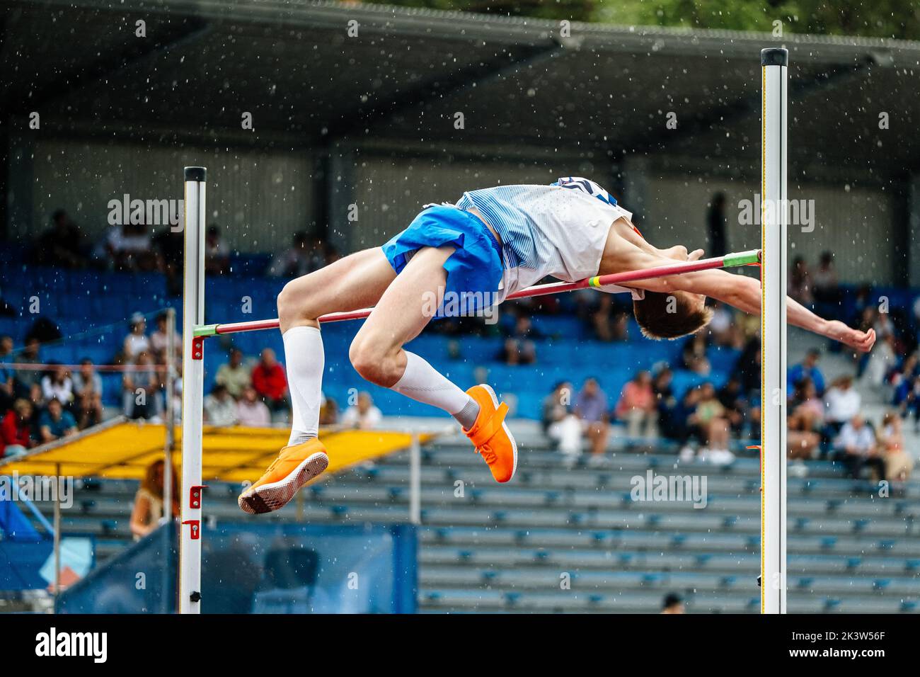 hombre jumper de competición alto salto bajo la lluvia Foto de stock
