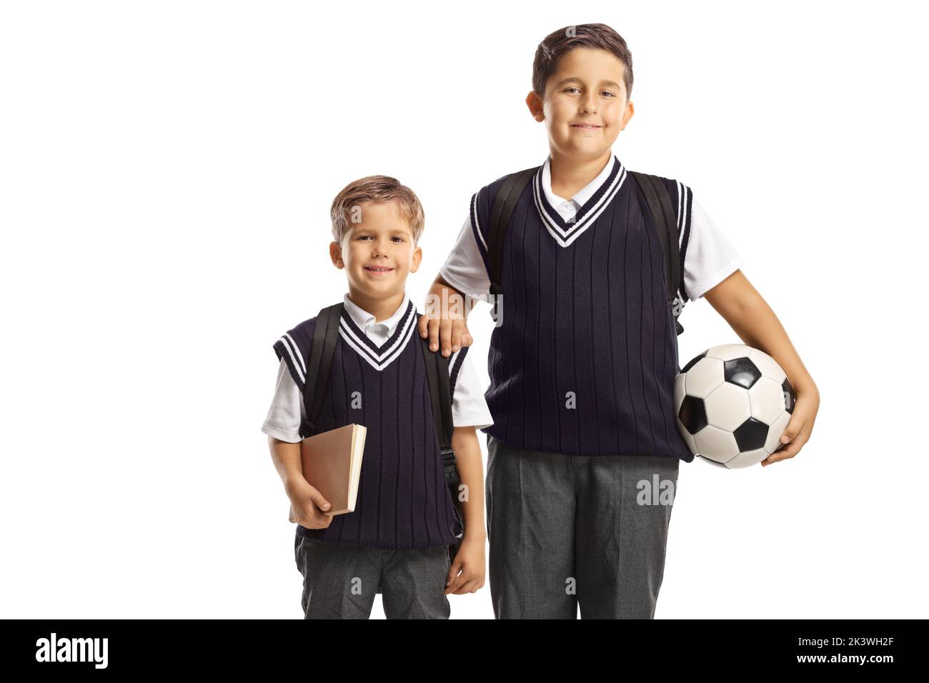 Hermanos con uniformes escolares y un balón de fútbol aislado sobre fondo blanco Foto de stock