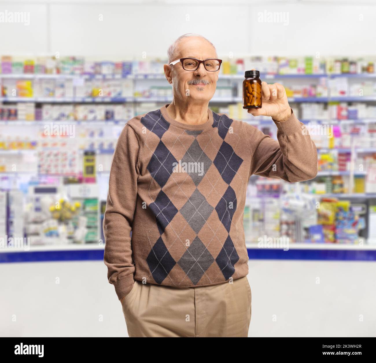 Hombre maduro sosteniendo una botella de píldoras dentro de una farmacia Foto de stock