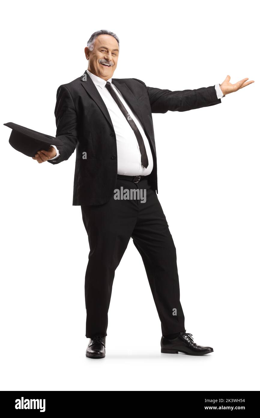 Hombre maduro alegre en traje negro y corbata bailando y sosteniendo un sombrero aislado sobre fondo blanco Foto de stock