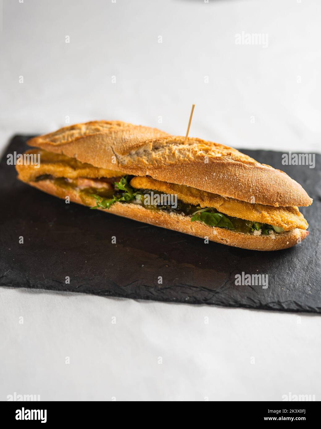 Un primer plano de un delicioso sándwich recién hecho sobre una pizarra negra Foto de stock