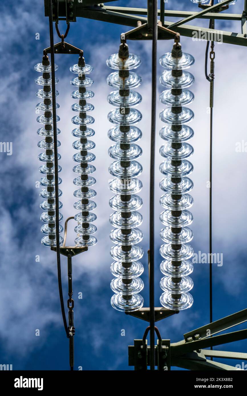 Aisladores hechos de vidrio en una línea de alta tensión, en los postes cuelgan como un dispositivo de suspensión entre el poste y el cable vivo, no aislado, ext Foto de stock