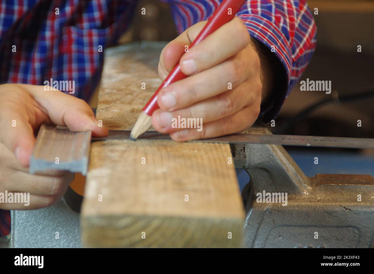El carpintero en el taller prepara una tabla de cortar materia prima. Trabajador de carpintero en taller de carpintería. Un experto y un artesano cuidadoso centrado en el trabajo. Foto de stock