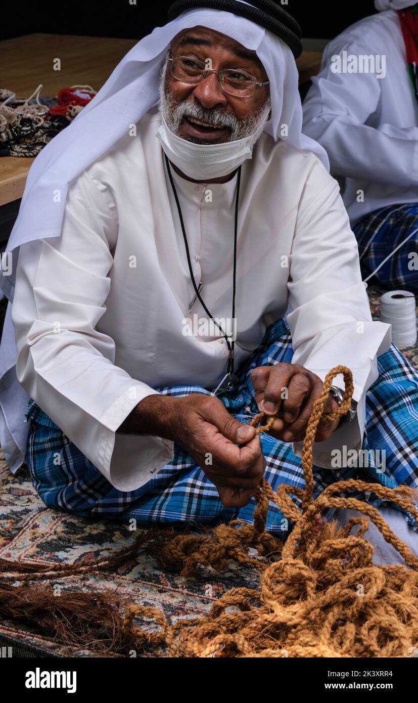 Afro-árabe de Abu Dhabi en el Festival Folklife en Dishdasha, Ghutra y Agal, haciendo cuerda de fibra de coco para su uso en la fabricación de redes de pesca tradicionales. Foto de stock