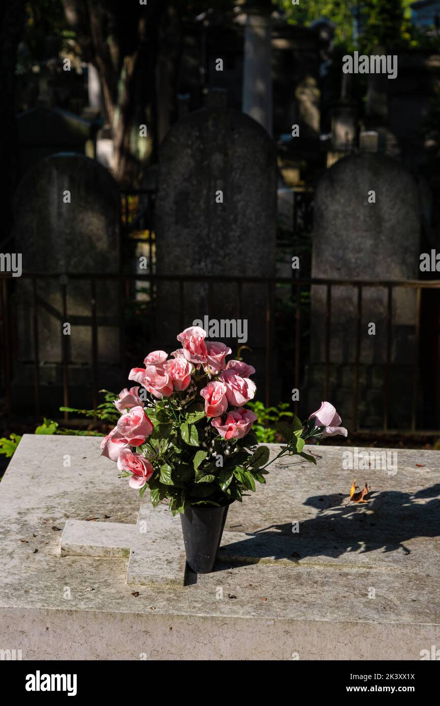 Rosas en un jarrón, en una lápida en el cementerio Pere-Lachaise en París, Francia Foto de stock