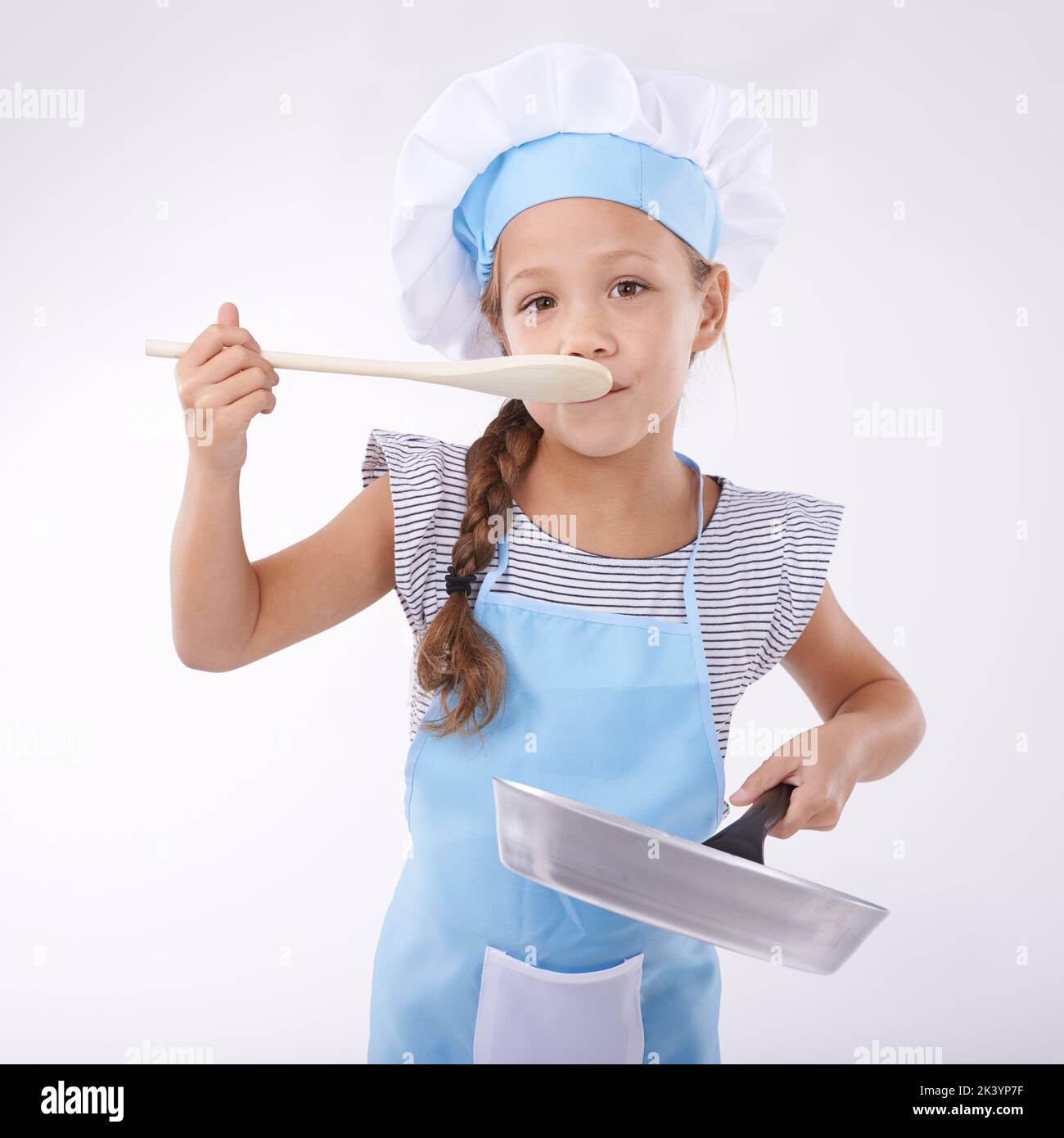 Aprender a cocinar. Retrato de una niña sosteniendo utensilios de cocina. Foto de stock
