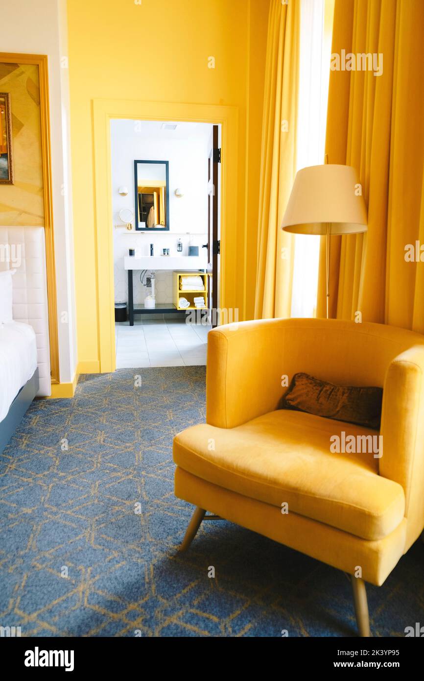 Plano vertical de una habitación amarilla brillante con cortinas amarillas y una silla amarilla con lámpara de lectura Foto de stock