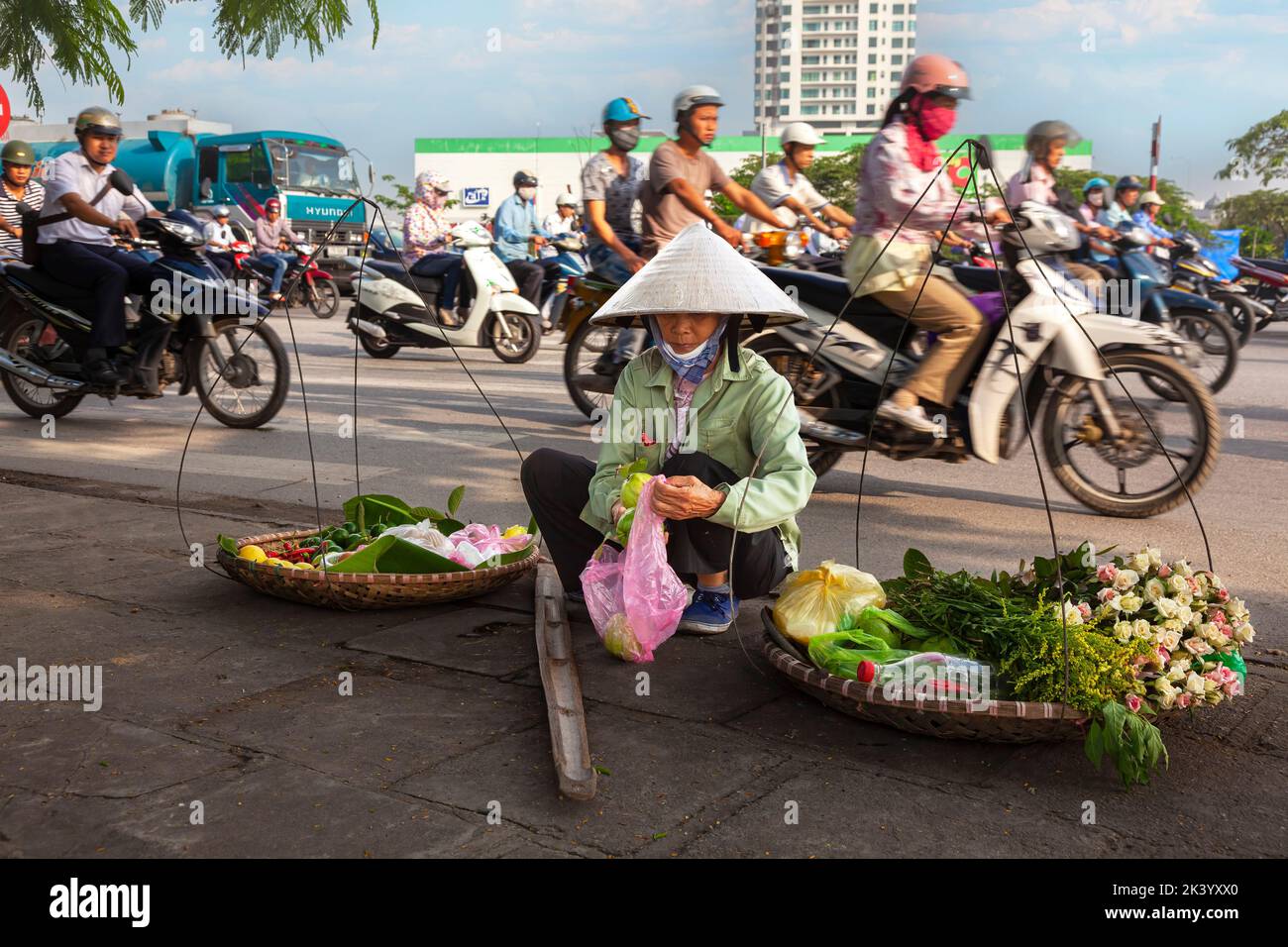 Vendedor ambulante vietnamita usando sombrero de bambú vendiendo comida de pannier en la calle, Hai Phong, Vietnam Foto de stock